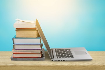 Stack of books with laptop on wooden