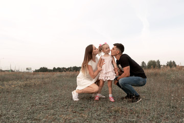 Mom, dad, daughter in meadow. Happy family in nature.