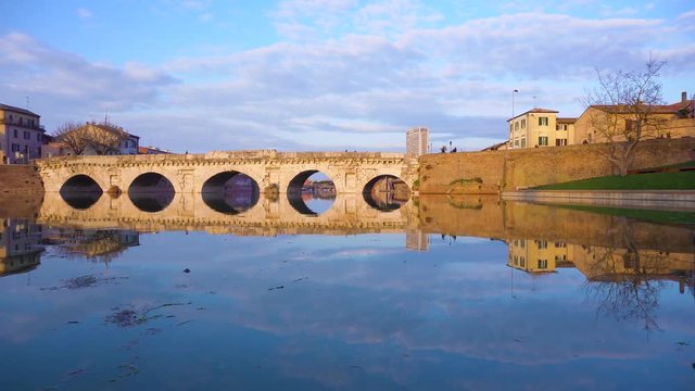 view of roman bridge reflecting in water in Rimini, Italy