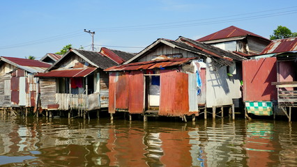 Fototapeta na wymiar einfache Hütten in Borneo stehen auf Stelzen im Fluss Martapura und spiegeln sich im Wasser 