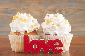 Cupcake and word Love on wooden table.