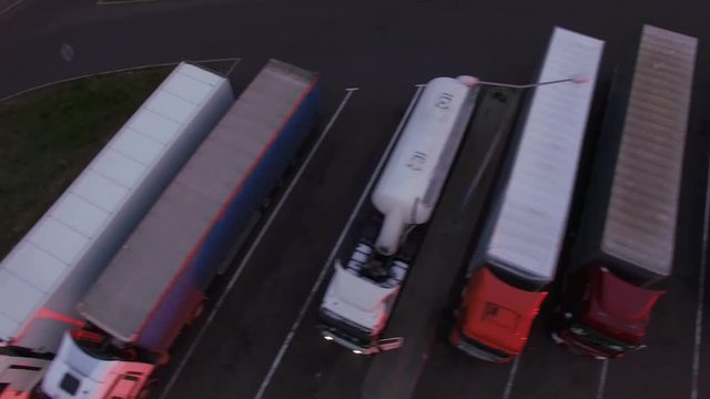 4k horizontal tracking shot flight over vans lorry standing in rows close up asphalt lines. Drone helicopter flying over trucks cars vehicles on parking lot resting drivers sleeping in evening morning