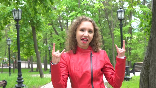Young woman make that rocks or ILY or Devil Horns sign by both hands to the camera