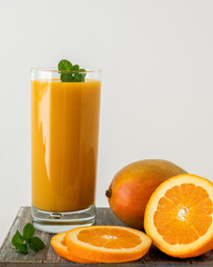 glass of mango and orange juice and fresh fruits isolated on white