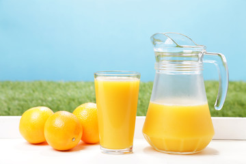 Obraz na płótnie Canvas Fresh oranges, glass and jar full of orange juice