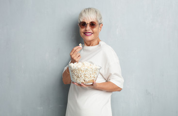 senior cool woman with pop corns against grunge cement wall. cinema concept