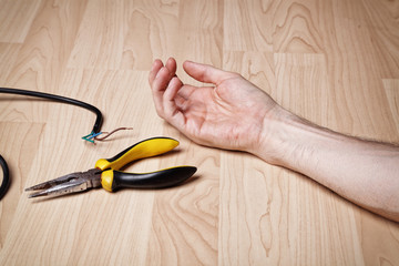 Hand of a man lying on the floor after an electricc shock