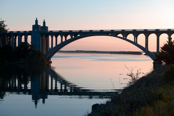 Rogue River bridge in Gold Beach, Oregon at sunset reflected in water