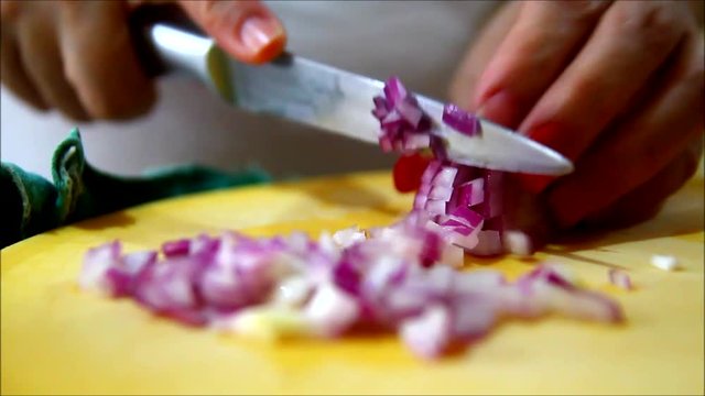 Hand held close up video of hand slicing or chopping shallot or onion