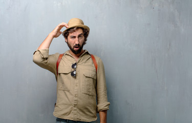 young traveler man or tourist with a goofy, dumb, silly look, feeling shocked and confused at a...