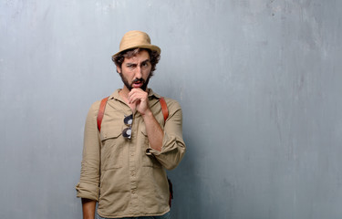 young traveler man or tourist with a goofy, dumb, silly look, feeling shocked and confused at a...