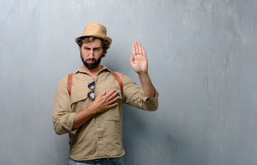 young traveler man or tourist smiling confidently while making a sincere promise or oath, solemnly...