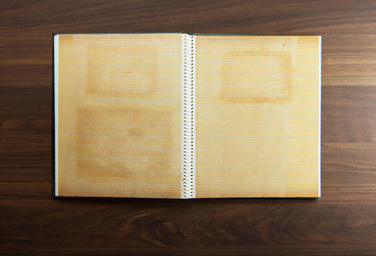 Blank page of an 1970s photo album, on a dark colored wooden table.