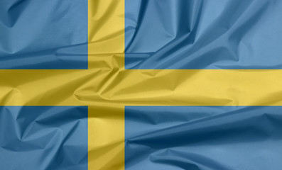 Fabric flag of Sweden. Crease of Swedish flag background, it is consists of a yellow or gold Nordic Cross on a field of blue.