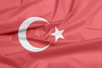 Fabric flag of Turkey. Crease of Turkish flag background, a red field with a white star and crescent slightly left of center.