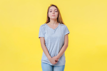 Girl on a yellow background is in a closed pose. Looks with indifference and contempt arrogant