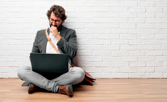 young man sitting on the floor Coughing, suffering a winter illness such as a cold or the flu, feeling unwell and feverish.