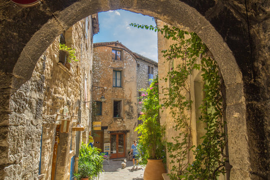 Fototapeta Looking through an arch at a quaint side street in Tourrettes-sur-Loup, France