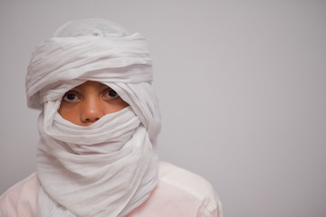 Boy with a white headscarf standing against white background