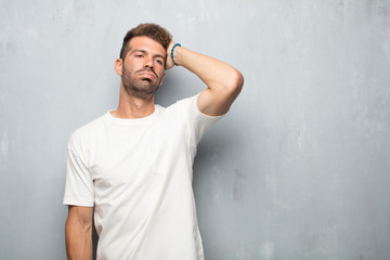 young handsome man looking unenthusiastic and bored, listening to something dull and tedious and...