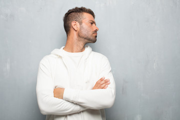 young handsome man with a dissenting, serious, stern expression, with crossed arms in disapproval.
