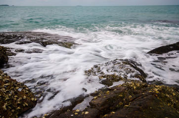 Sea waves crashing to rocks creating foam.