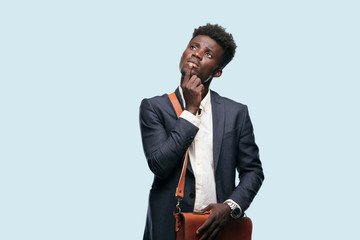 young black businessman With a confused and thoughtful look, looking sideways, thinking and wondering between different options. - obrazy, fototapety, plakaty