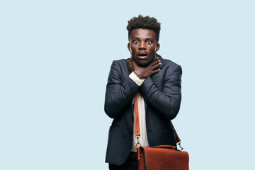 young black businessman screaming, looking surprised, stressed and terrified, with a gesture of...