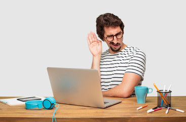 young bearded graphic designer with a laptop paying attention, trying to hear and listen to what is...