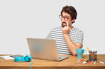 young bearded graphic designer with a laptop looking, observing, keeping an eye on an object in...