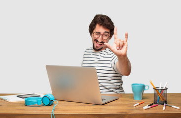 young bearded graphic designer with a laptop singing rock, dancing, shouting, gesturing in a...