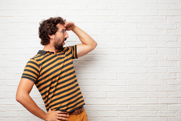 young dumb man looking far off into the distance, searching for a distant object with a confused...