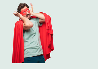 crazy man as a super hero with both hands covering ears to protect them from an uncomfortable,...