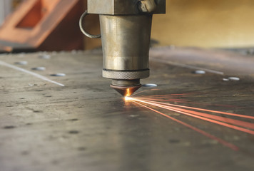 laser machine cuts a thick sheet of metal with sparks