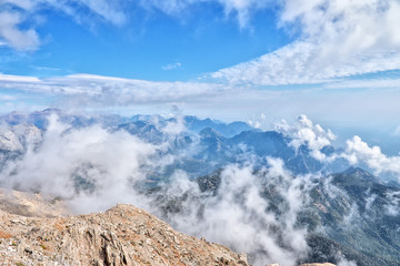 View from the Peak of Tahtali Mountain or Olympus to the tops of the Taurus Mountains, against the background of the cloud and the blue sky