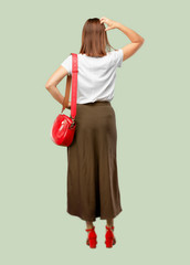 young pretty woman back view, hand on hip and scratching head with the other hand, as if confused...