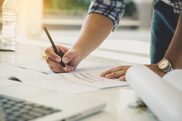 Close up engineer drawing hands working on architectural project at construction site at desk in office.