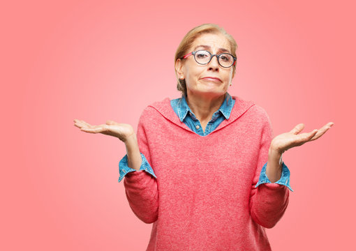 Beautiful Senior Woman With A Quizzical And Confused Look, Doubting Between Different Choices Or Possibilities With A Wondering Expression, Comparing And Posing A Question.