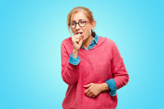Beautiful adult blonde woman Coughing, suffering a winter illness such as a cold or the flu, feeling unwell and feverish.