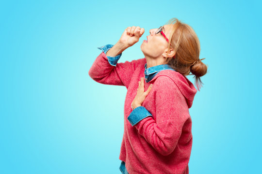 Beautiful adult blonde woman Coughing, suffering a winter illness such as a cold or the flu, feeling unwell and feverish.