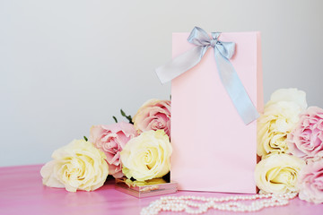 Perfume, gift, pearls, gentle roses on a pink background.