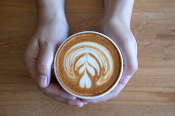 women  Holding coffee cup, wooden table  cafe while having coffee