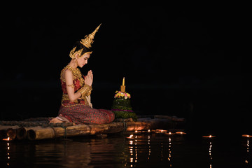Obraz premium Young model asian girl in thai dress holding hand play respects Ganges river in loy kratong festival at night time in Thailand 