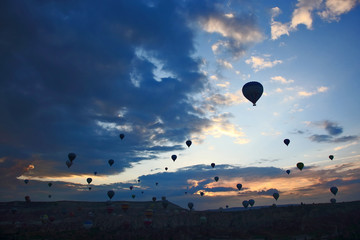 Many passenger balloons fly against the background of dawn in the clouds