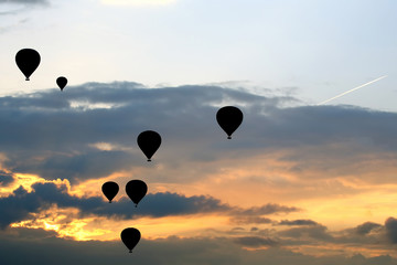 Many passenger balloons fly against the background of dawn in the clouds