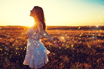 Young woman on field under sunset light