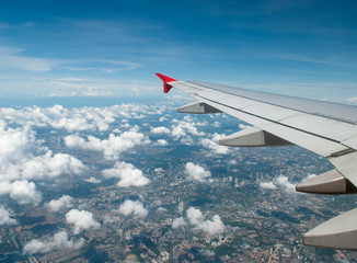 Obraz premium wing of airplane flying above clouds