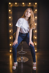 Girl in white tee-shirt in studio near the frame with lights