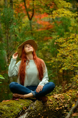 Obraz premium Young redhead woman sitting in autumn park