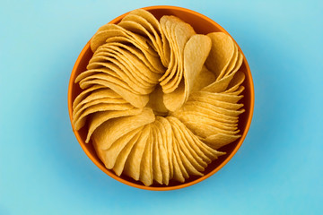 top view  orange bowl full of potato chips blue pastel background